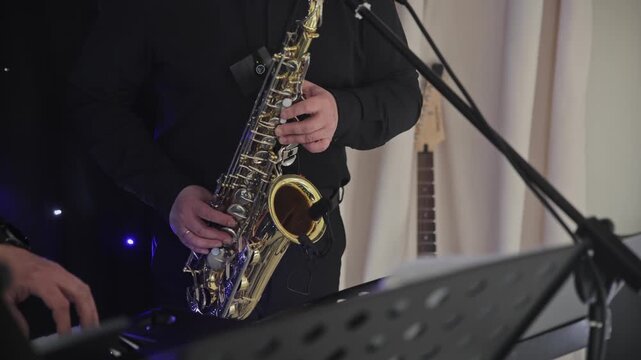 Close-up of a saxophone player performing with a keyboard musician during a live indoor event, concert or celebration.