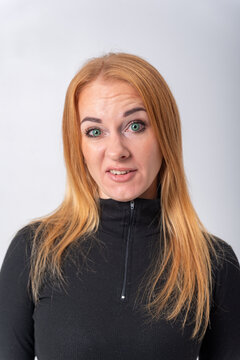 Young woman with red hair and green eyes reacting with a strong negative facial expression, showing feelings of disgust, aversion, and disapproval, isolated on a white background