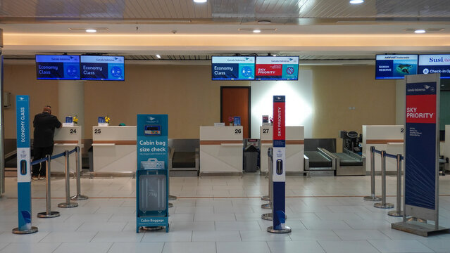 Check-in counter desk area with economy class and priority screens for passenger departures at Hang Nadim Airport in Batam, Indonesia. Modern airport terminal interior view for travel concept.