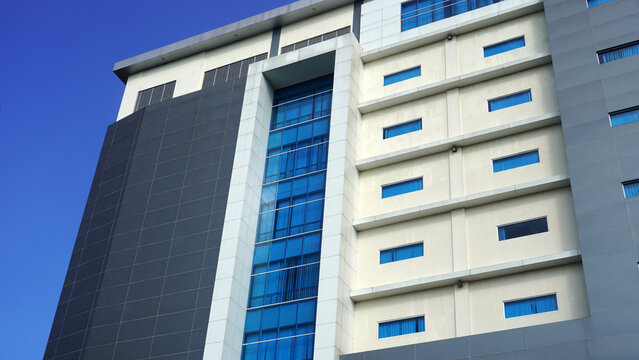 High-rise building facade highlighting a tall vertical glass stairwell panel flanked by rows of small windows.