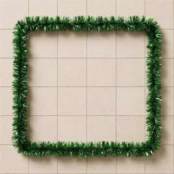 Green tinsel garland border frame on beige tile background with copy space for Christmas