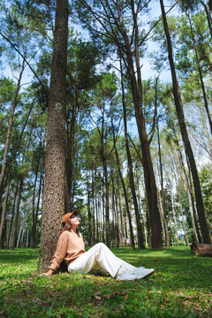 Vertical portrait image of a woman sitting and relaxing in the park