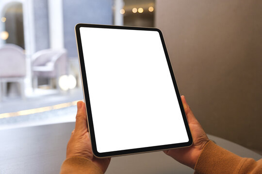 Mockup image of a woman holding digital tablet with blank white desktop screen in cafe