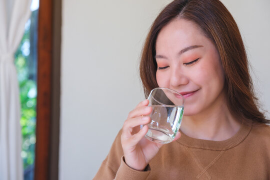 Portrait image of a woman holding and drinking water at home