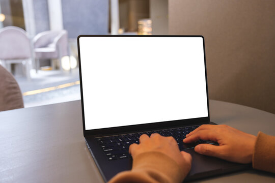 Mockup image of a woman working and typing on laptop computer with blank white desktop screen