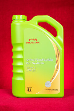 ZhongShan GuangDong China-September 10 2026: A GAC HONDA full synthetic gasoline engine oil plastic jug against red background.