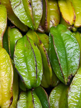 Green starfruit carambola stacked in ridged rows filling the whole frame