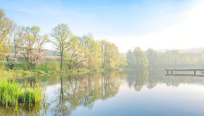 Fototapeta premium Serene lake landscape with trees, reflections and a wooden pier