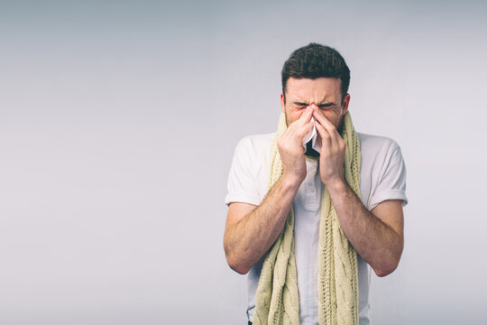 studio picture from a young man with handkerchief. Sick guy isolated has runny nose. man makes a cure for the common cold.Nerd is wearing glasses
