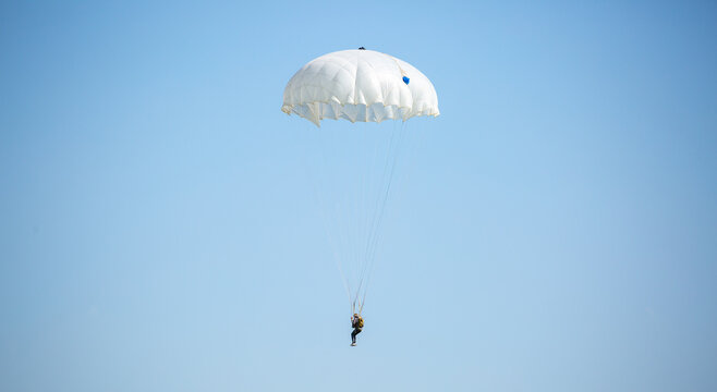 Skydiving. Flying parachutists against the background of the blue sky and mountains. Extreme sport and entertainment.