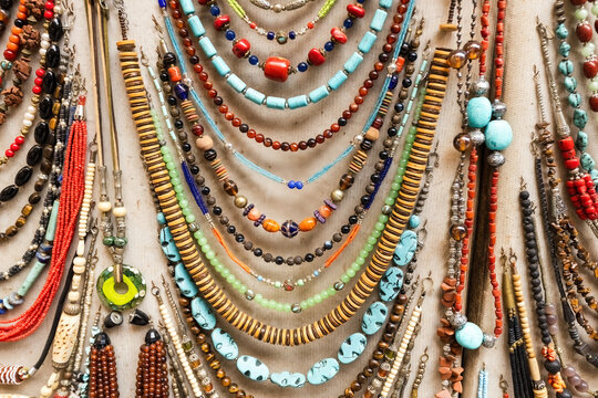 A vibrant collection of traditional Moroccan beaded necklaces and jewelry displayed on fabric in a market stall in the medina of Fez, Morocco