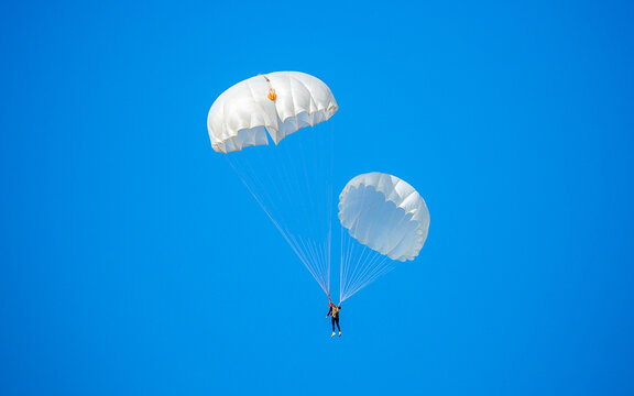 Skydiving. Flying parachutists against the background of the blue sky and mountains. Extreme sport and entertainment.