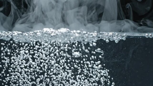 Bubbles rise through clear liquid under a cloud of steam against a dark background.