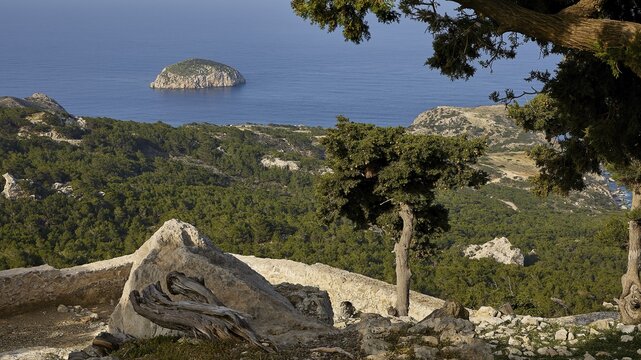 A rocky landscape with trees and a view of a small island in the sea, under a blue sky, Kastro Monolithou, Monolithos Castle, rock castle, Monolithos village, Rhodes, Dodecanese, Greek Islands, Greece