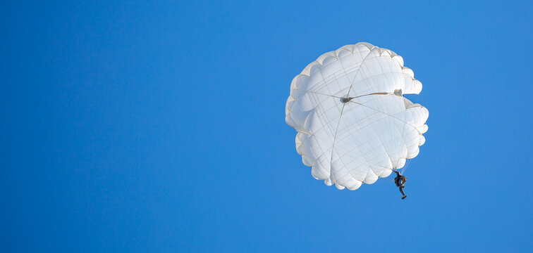 Skydiving. Flying parachutists against the background of the blue sky and mountains. Extreme sport and entertainment.