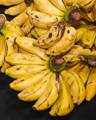 Ripe yellow bananas fanned out in hands against a dark background © Bugra Kaan Ersoy