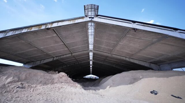 Huge piles of livestock feed filling an industrial storage barn on a rural farm