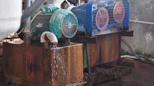 Industrial water pump and electric motor with rusted components on a farm