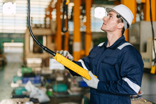 Young man worker factory engineer technician hoist crane operating in industrial plant factory.