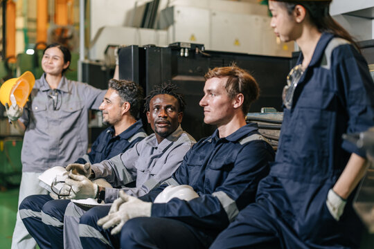 Diverse factory engineering team sitting relax talking and discussing work in manufacturing plant