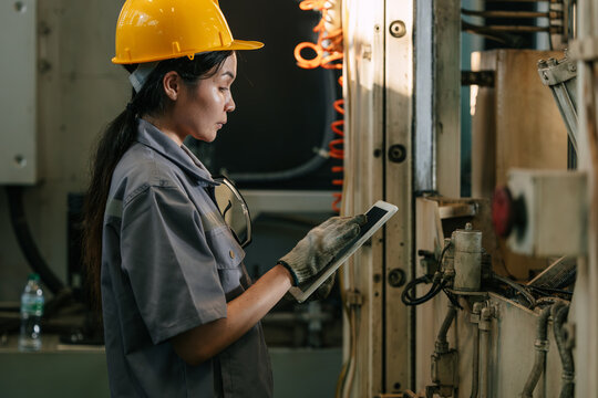 Professional Young Female industrial engineer worker inspecting machinery with tablet