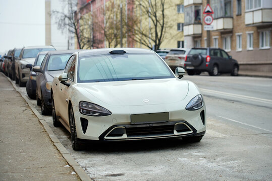 Minsk, Belarus. Feb 14, 2025. Modern Xiaomi SU7 electric sedan parked along city street curb with other parked cars and urban residential buildings in background. Xiaomi electric car parked