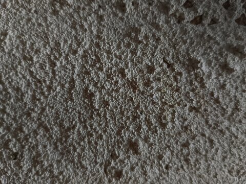 Close up texture of white expanded polystyrene foam surface with harsh shadows.