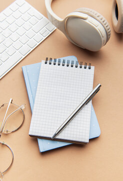 Workspace with notebook, pen, headphones, and keyboard