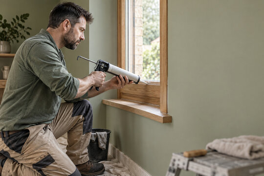 Technician sealing a window frame