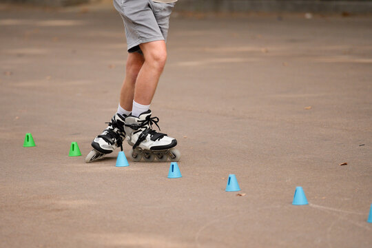 Man practicing slalom roller skating with cones outdoors