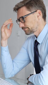 Businessman experiencing stress and headache while working on computer, feeling overworked, tired, and suffering from digital eye strain in an office setting