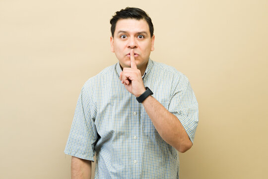 Latin man making shush gesture, keeping a secret, asking for silence and quiet, indicating privacy