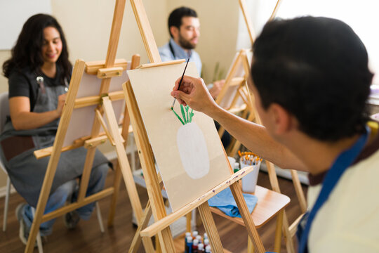 Friends enjoying art class, learning to paint on canvas during a creative leisure activity