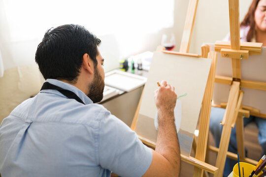Young man learning painting at an art class, developing creativity and artistic skills during hobby workshop