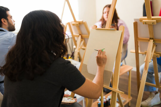 People enjoying an art class, painting with brushes and acrylics on canvas, learning new artistic techniques