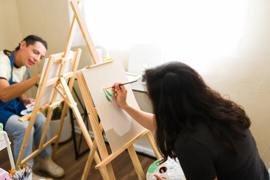 Group of young people enjoying an adult art class, painting on easels in a studio, expressing their artistic passion