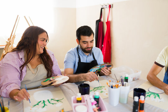 Diverse group of people painting on canvas with acrylics during an art class, fostering creativity and artistic expression