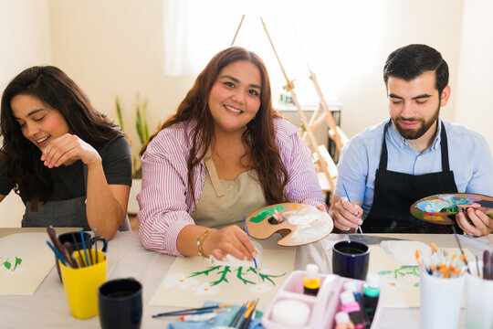 Diverse adults enjoying art class, painting with brushes and palettes, focusing on creative hobbies in a workshop