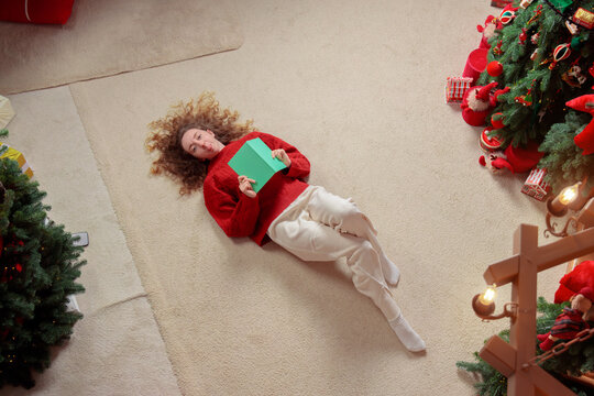 Young woman lying on the floor with a notebook in a cozy festive holiday home environment