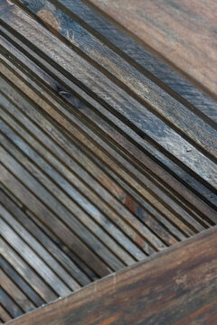 Close-up of weathered wooden slats arranged in diagonal parallel lines, creating an abstract natural texture with rustic brown tones and geometric repetition.
