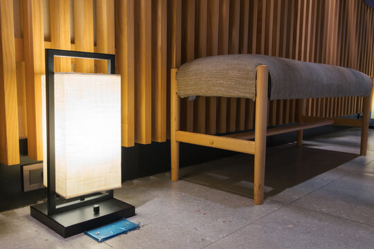 Zen style interior detail featuring a glowing contemporary floor lamp and wooden louver partition in a cozy room.