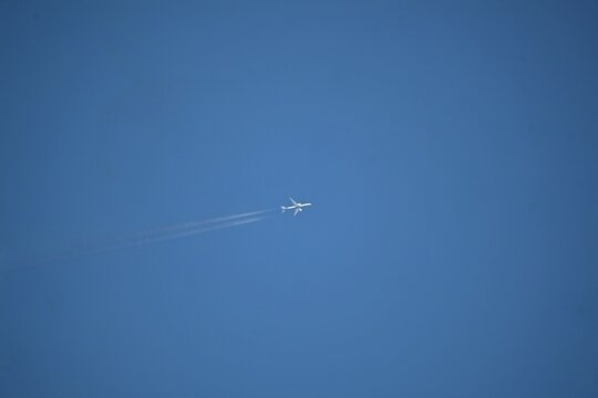 Passenger airplane flying across a clear blue sky leaving contrails