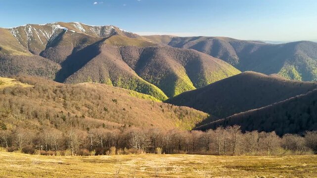   
Spring drone view of Borzhava ridge in Ukraine&rsquo;s Carpathians, lush green beech forest below and snow-covered peaks above, vivid seasonal contrast of renewal and lingering winter