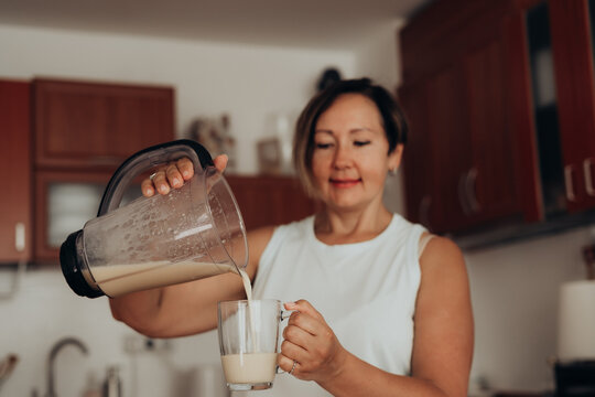 Woman scoops psyllium husk near blender for healthy kitchen routine focused on plant fiber digestive health microbiome balance functional food nutrition and gluten free baking