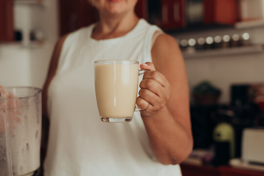 Mature woman shows fresh psyllium smoothie at home after blending fiber supplement drink for healthy digestion microbiome support soluble fiber nutrition and daily wellness routine