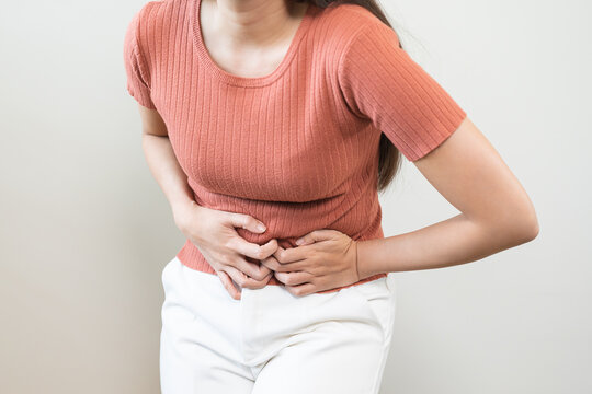 Flatulence asian young woman intolerance hand in stomach ache, suffer from food poisoning, abdominal pain and colon problem, gastritis or diarrhoea when at home. Patient belly, abdomen or inflammation