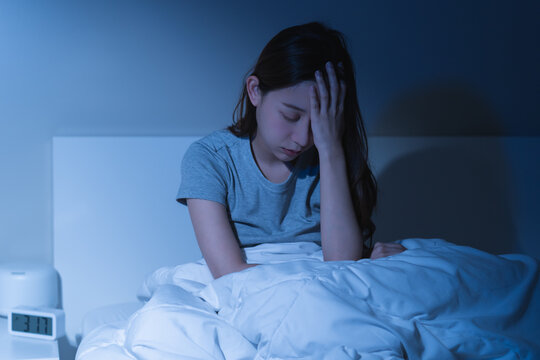 Sad worried and stressed, depressed asian young woman, girl suffering in bed from insomnia problem, awake at night, hand covering face from trouble disturbed loud noise, unable sleep. Restless people.