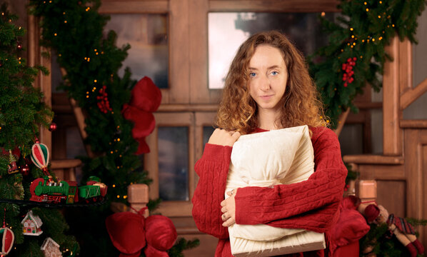 Candid portrait of a young woman holding a gift in a cozy cottage with festive Christmas decor