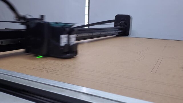 Industrial garment plotter printer drawing pattern outline on kraft paper
Close up view of an industrial automatic plotter machine head moving fast and drawing garment body pattern.