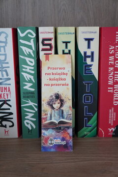 Row of colorful book spines with a decorative bookmark featuring an illustration of a young reader